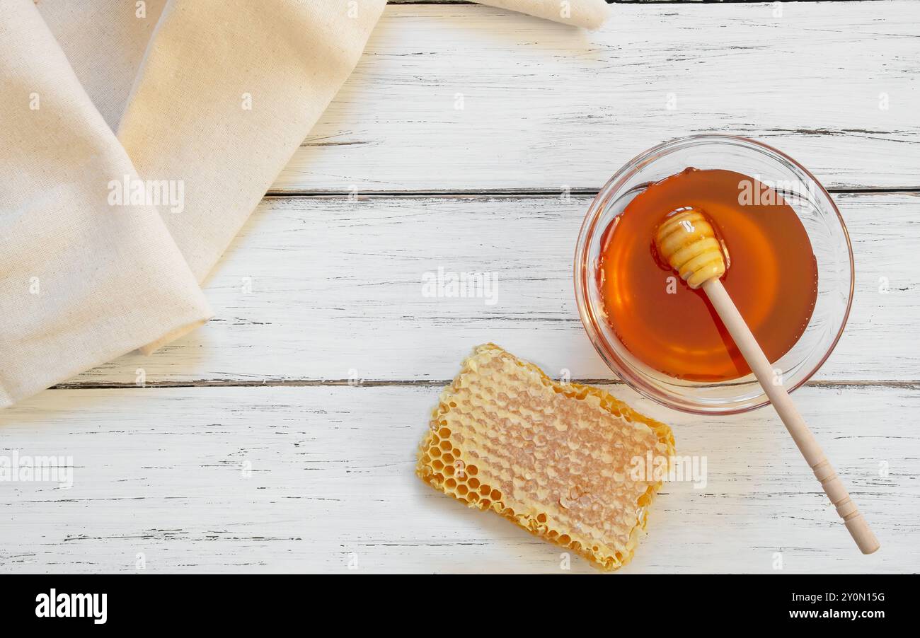 Morceau de miel frais biologique en nid d'abeille avec une trempette sur fond rustique, nourriture saine Banque D'Images