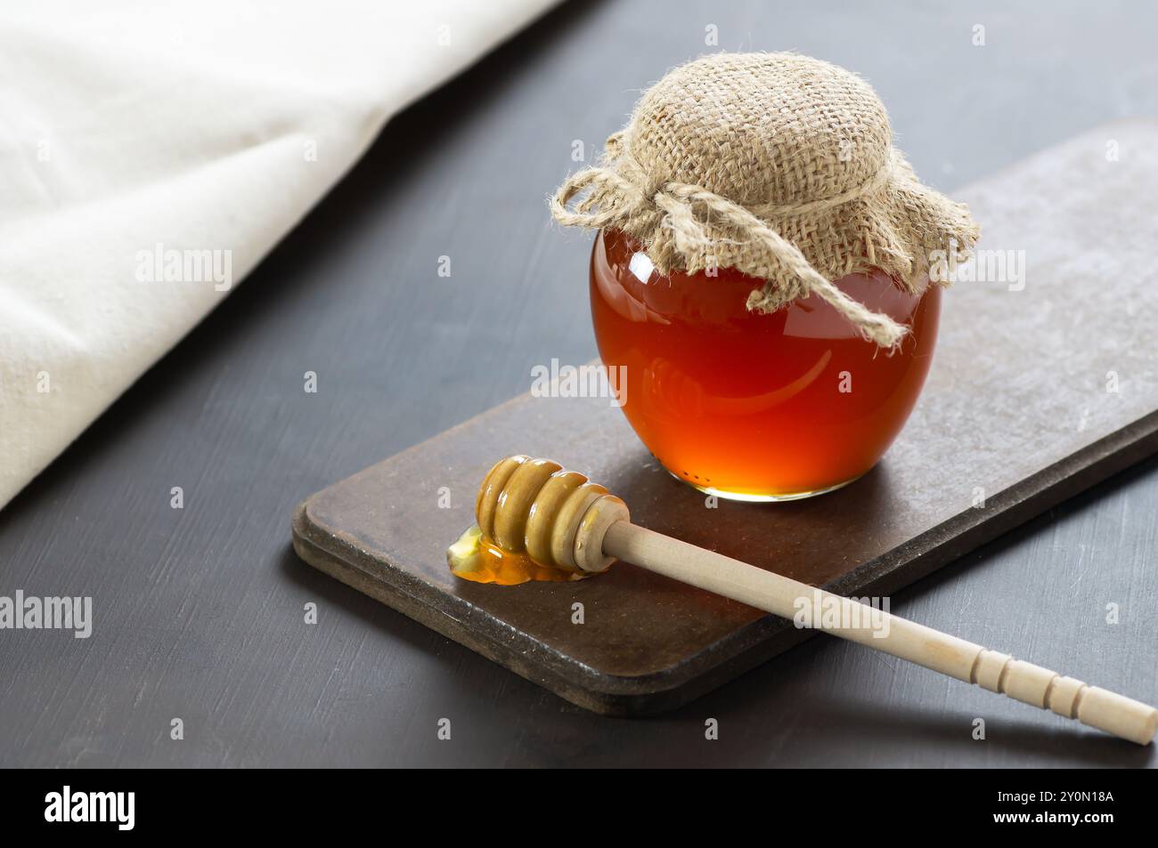 Miel liquide frais biologique dans un pot en verre ou un bol avec un plongeur sur fond rustique, nourriture saine Banque D'Images