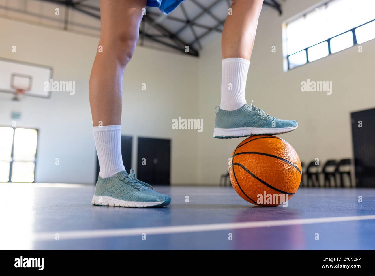 Jouer au basket-ball dans le gymnase de l'école, balle d'équilibrage de fille avec le pied Banque D'Images