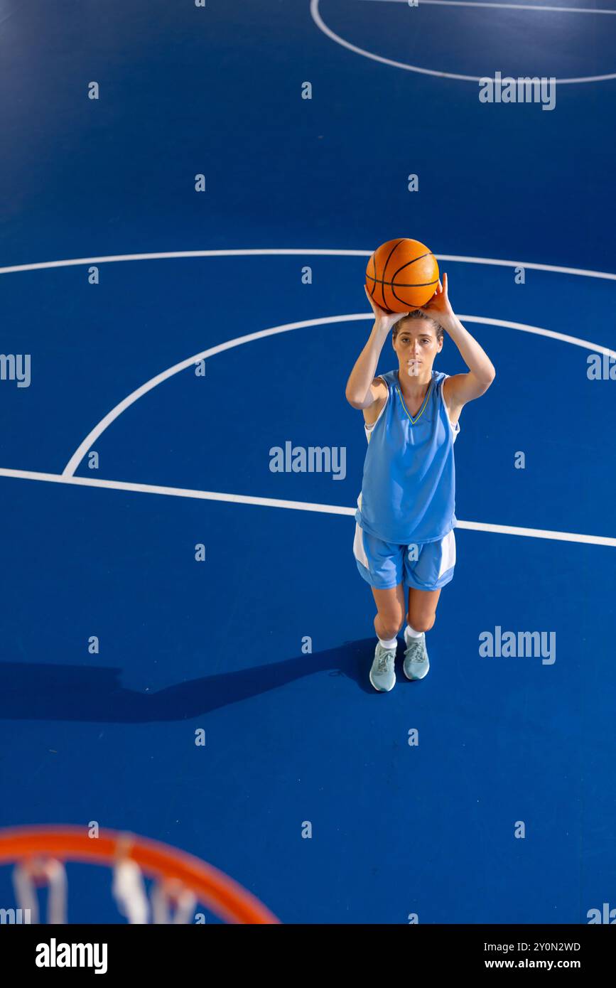 Jouer au basket-ball, femme visant à tirer la balle sur un terrain intérieur Banque D'Images