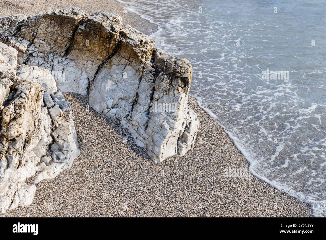 Roches côtières blanches gisent dans le sable humide sur la plage, photo naturelle Banque D'Images