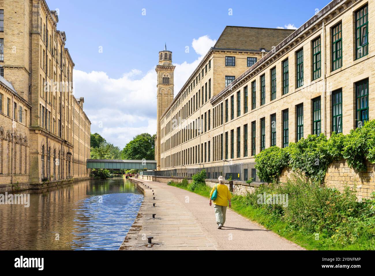 Femme marchant le long du canal à Salts Mill sur le canal de Leeds et Liverpool Saltaire Village Bradford, West Yorkshire Angleterre UK GB Europe Banque D'Images