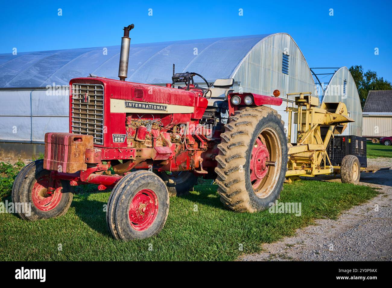 Tracteur rouge classique avec récolteuse jaune et serres au niveau des yeux ruraux Banque D'Images