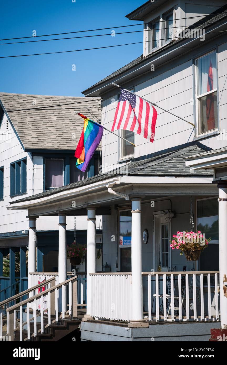 Un drapeau américain et LGBTQ volent l'un à côté de l'autre sur une vieille maison. Pendleton OREGON, États-Unis. Banque D'Images