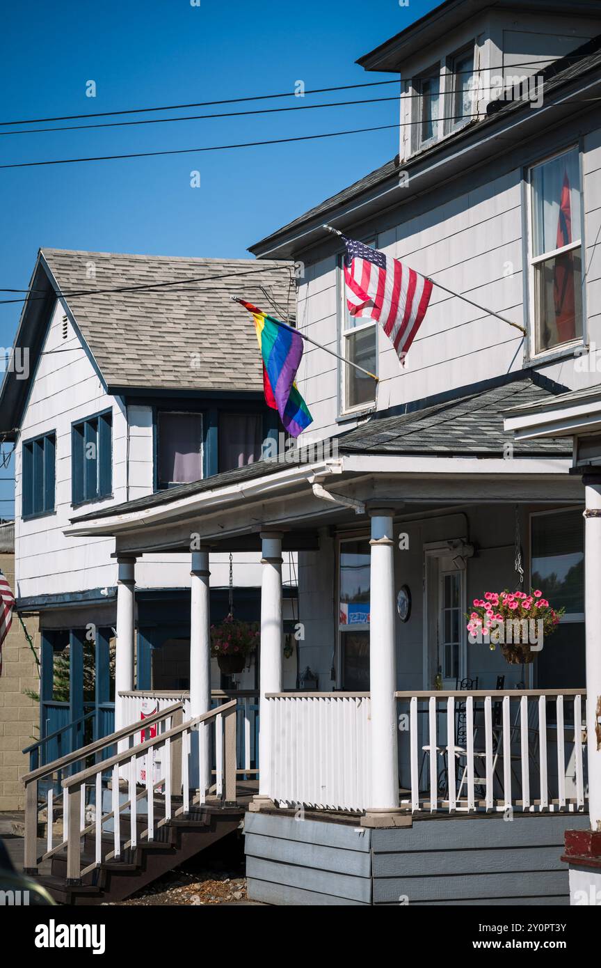 Un drapeau américain et LGBTQ volent l'un à côté de l'autre sur une vieille maison. Pendleton OREGON, États-Unis. Banque D'Images
