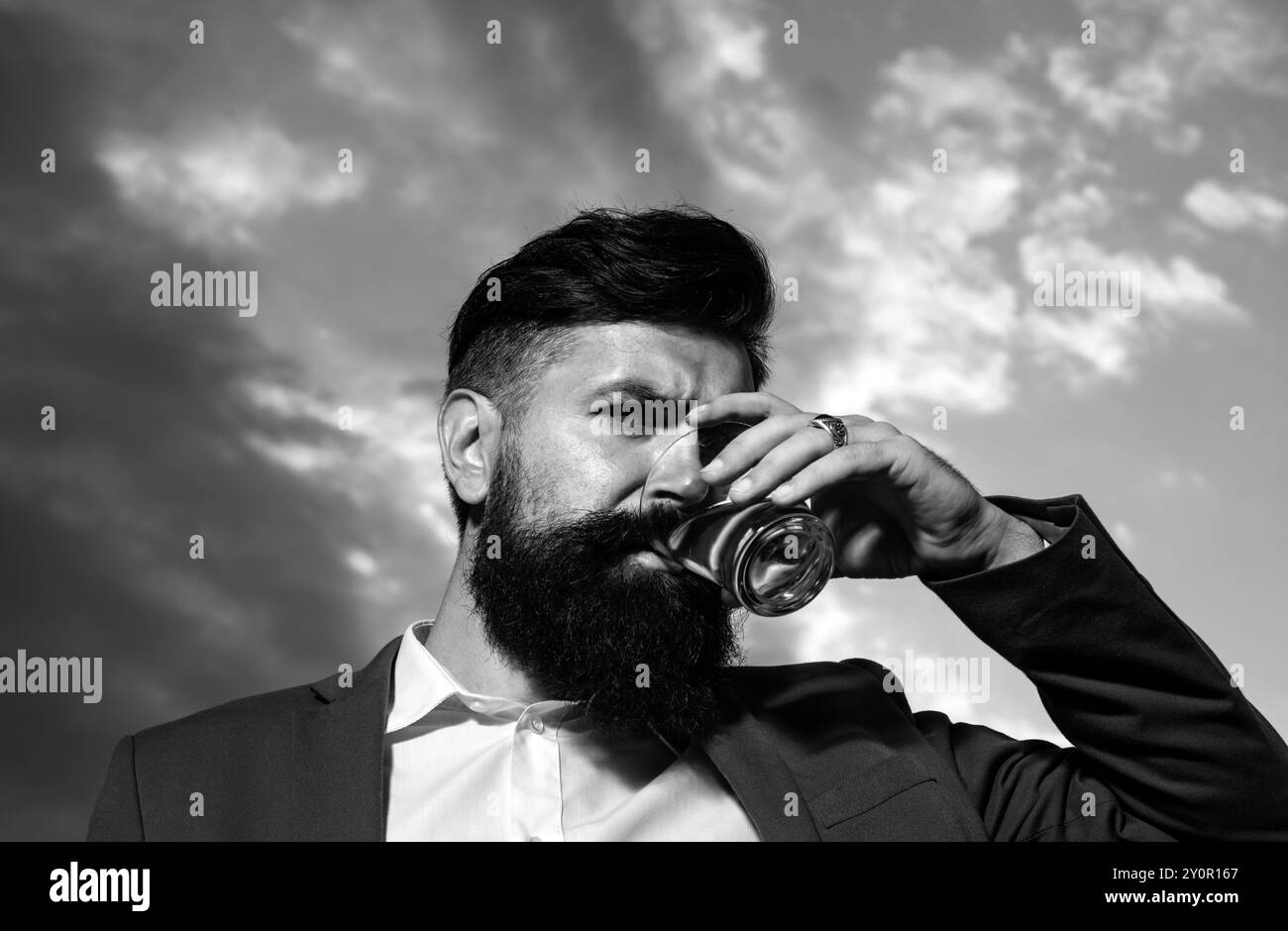 Gros plan sur un beau barbu plein de style qui apprécie le brandy ou le whisky. Banque D'Images