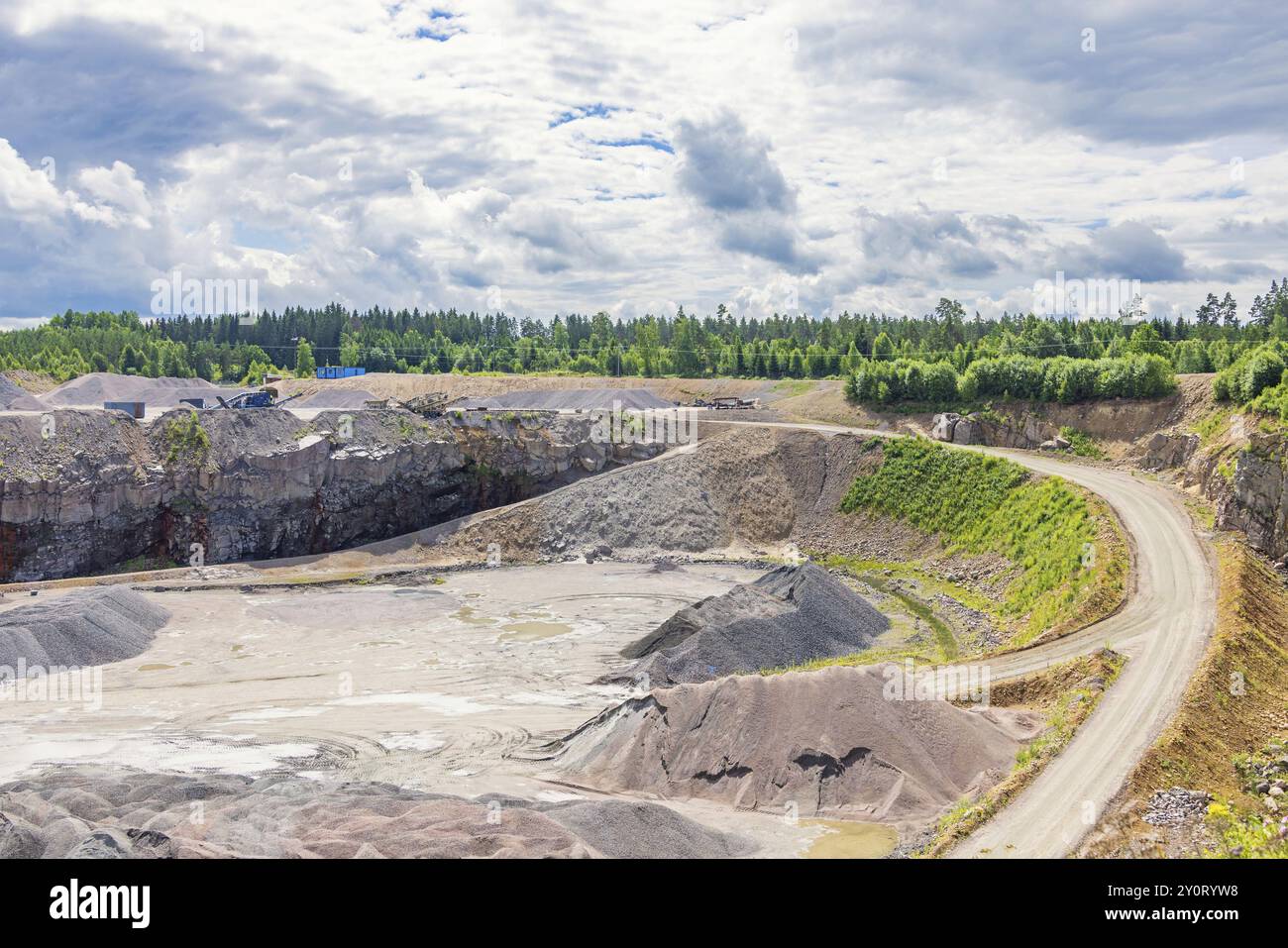 Route vers une fosse industrielle à ciel ouvert avec des tas de gravier dans la forêt Banque D'Images