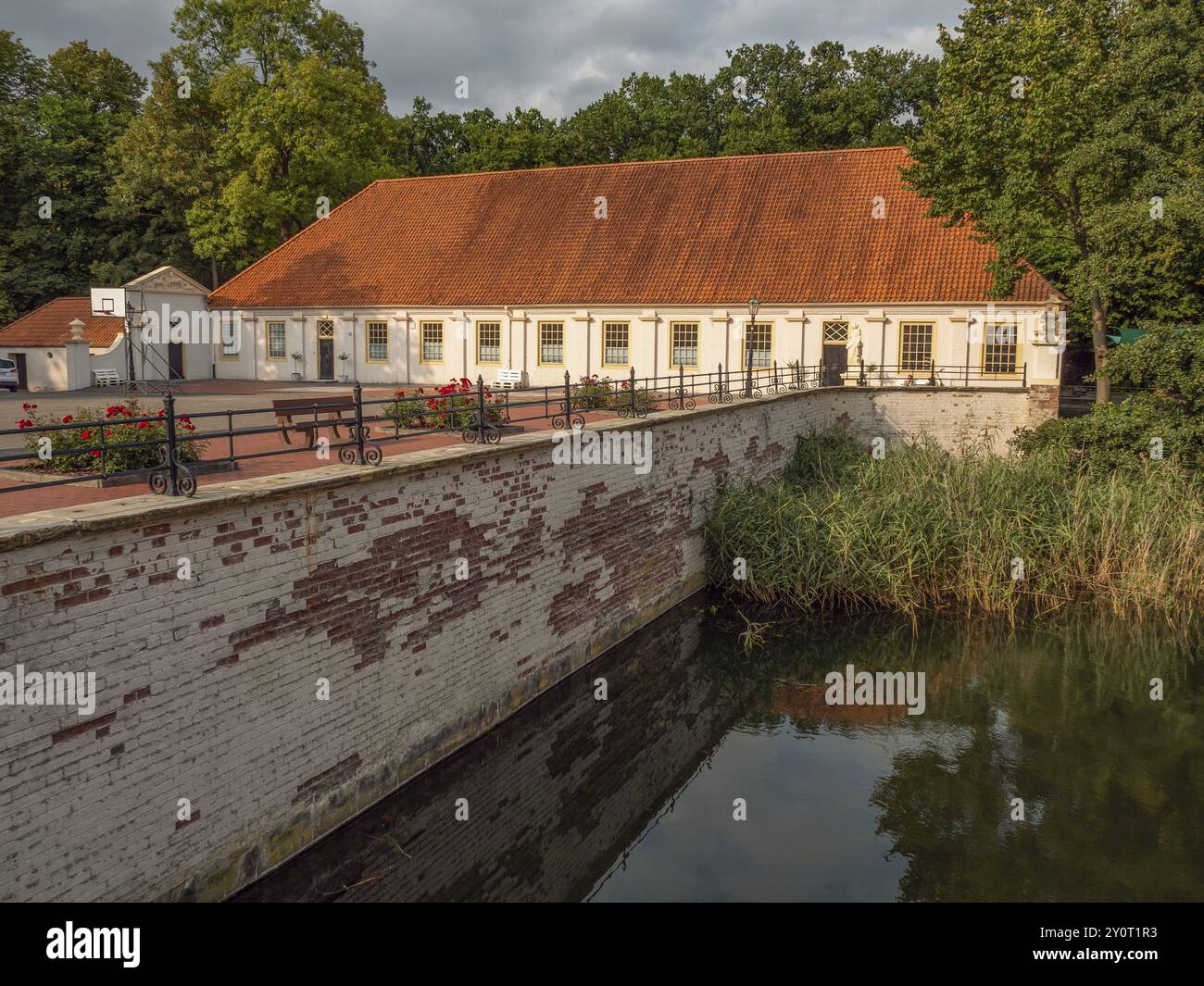 Long bâtiment avec toit en tuiles, douves et environnement verdoyant, dornum, frise orientale, allemagne Banque D'Images