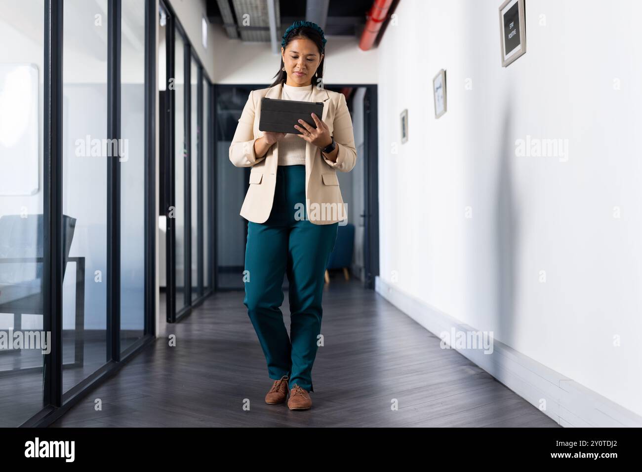 Marcher dans le couloir du bureau, femme utilisant la tablette pour les tâches de travail Banque D'Images