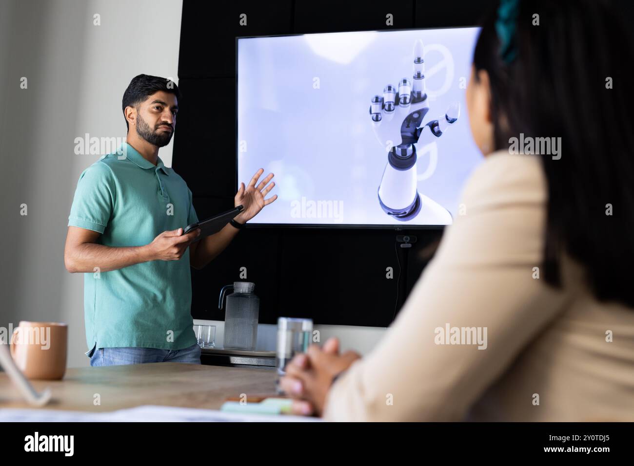 Présentant la conception robotique de la main, l'homme indien utilisant la tablette dans la réunion de bureau moderne Banque D'Images
