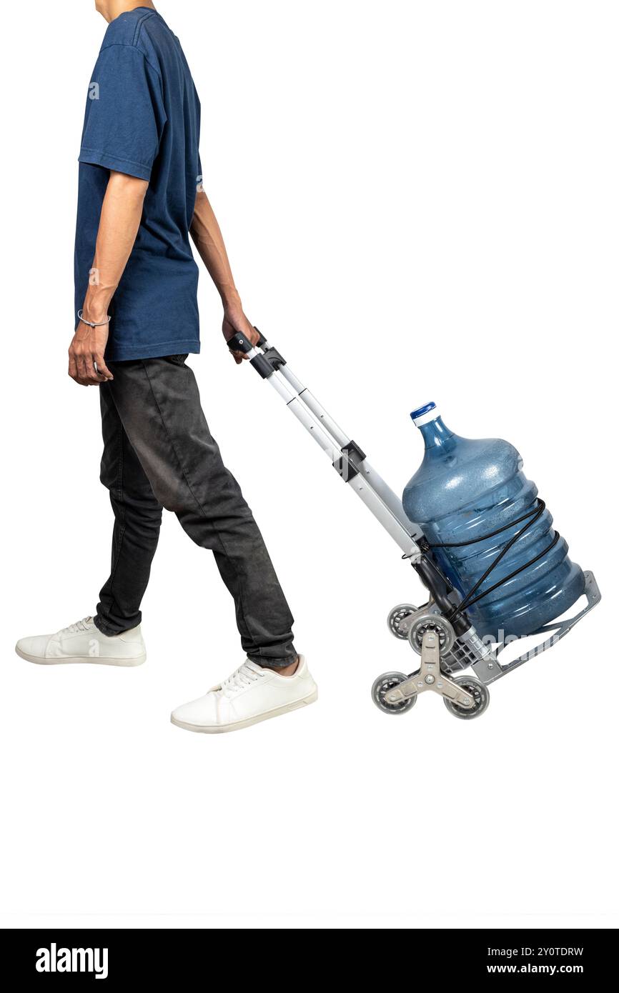 Un homme tire un chariot avec un gallon d'eau dessus. Le chariot est conçu pour transporter des bouteilles d'eau et est utilisé pour transporter la bouteille Banque D'Images