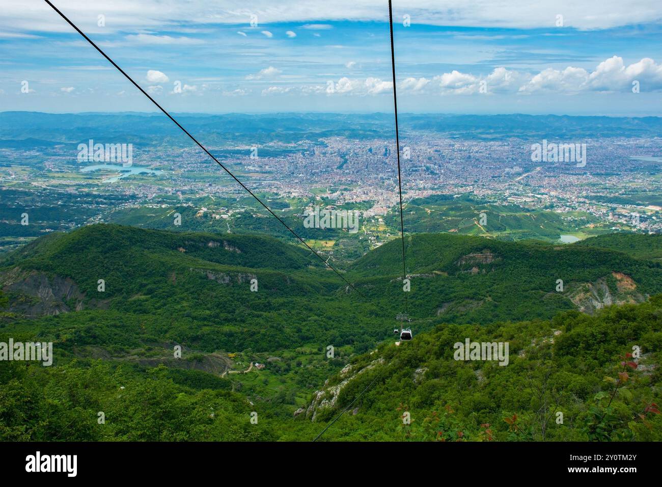 Un téléphérique monte sur le mont Dajti, offrant une vue panoramique à couper le souffle sur le paysage urbain tentaculaire en contrebas et la campagne verdoyante environnante Banque D'Images