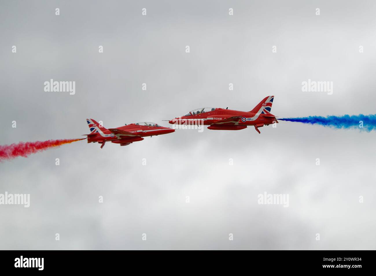 Célébrant leur 60e année d'opération, deux Hawker Siddeley Hawk jets de l'équipe britannique de voltige Red Arrows effectuent un cross over Banque D'Images