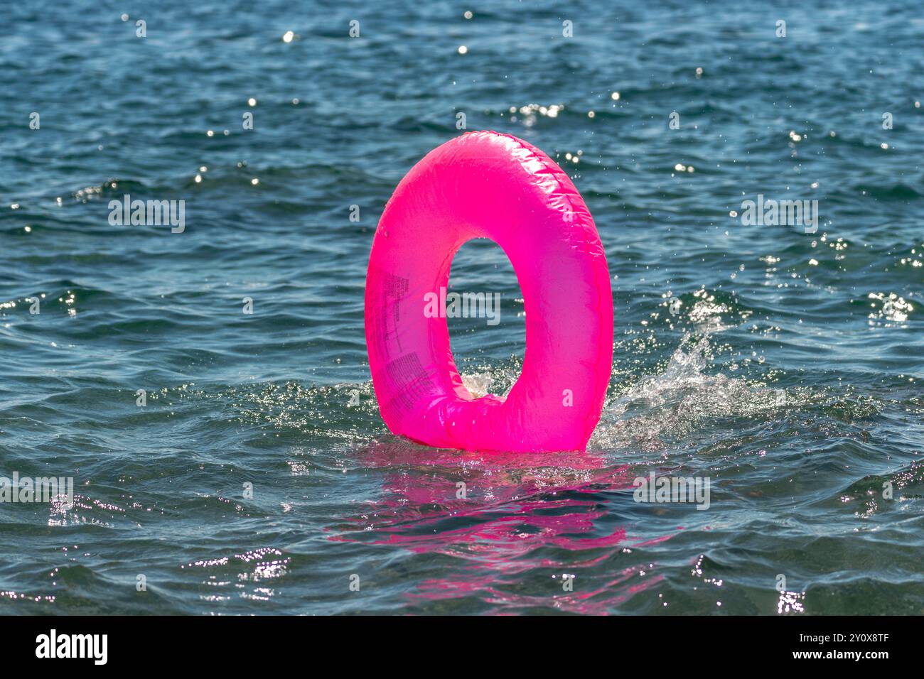 Plage de sécurité de l'eau d'anneau gonflable - anneau gonflable rose flottant dans l'eau pour la sécurité. Banque D'Images