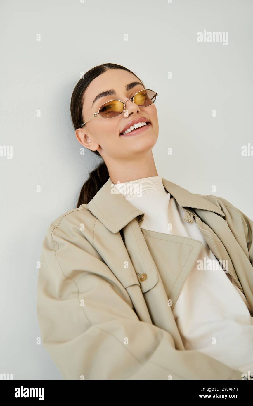 Une jeune femme chic et confiante présente sa tenue d'automne élégante dans un cadre de studio tendance, incarnant la mode saisonnière. Banque D'Images