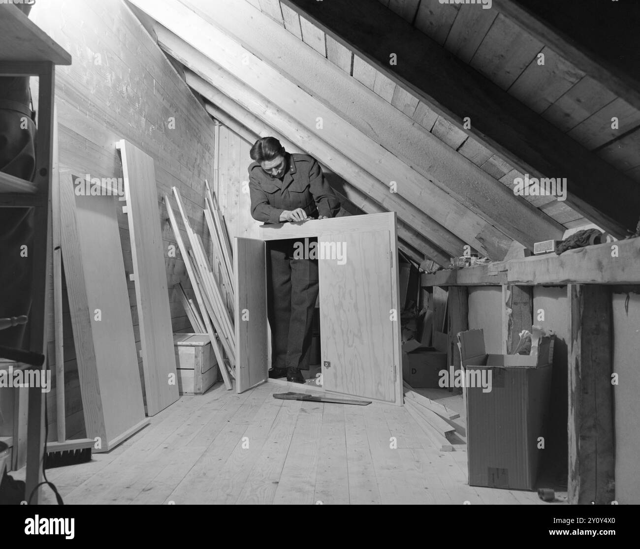 Réel 01- 1951 : la grande aventure. Mlle Mabel Melrose de Preston en Australie et le lieutenant Audun Fristad à Terningmoen avaient correspondu pendant 10 mois quand ils ont décidé qu'elle irait le long chemin à travers l'océan pour l'épouser. Ils ne s'étaient jamais vus, seulement écrit de longues lettres tendres, donc la décision qu'ils ont prise était plutôt audacieuse. Fristad est un homme maniable et un maître charpentier. Entre autres choses, il a fabriqué lui-même une grande partie du mobilier du salon. Ici, nous le trouvons dans le processus de menuiserie de placards pratiques pour la cuisine. Photo : Sverre A. Børretzen / Banque D'Images
