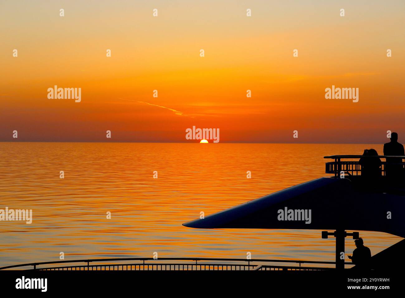 Les passagers de croisière en silhouette utilisent leurs appareils mobiles pour enregistrer le soleil couchant sur la mer Méditerranée, en route vers Barcelone, en Espagne. Banque D'Images