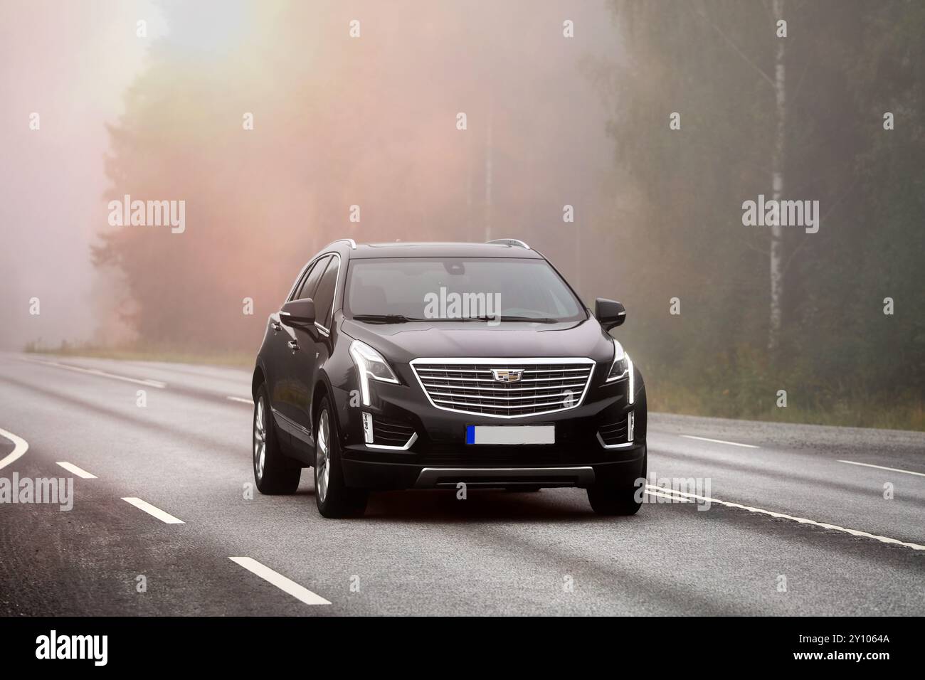 Voiture Cadillac noire et moderne à grande vitesse sur l'autoroute 10 par un matin brumeux. Humppila, Finlande. 8 août 2024. Banque D'Images