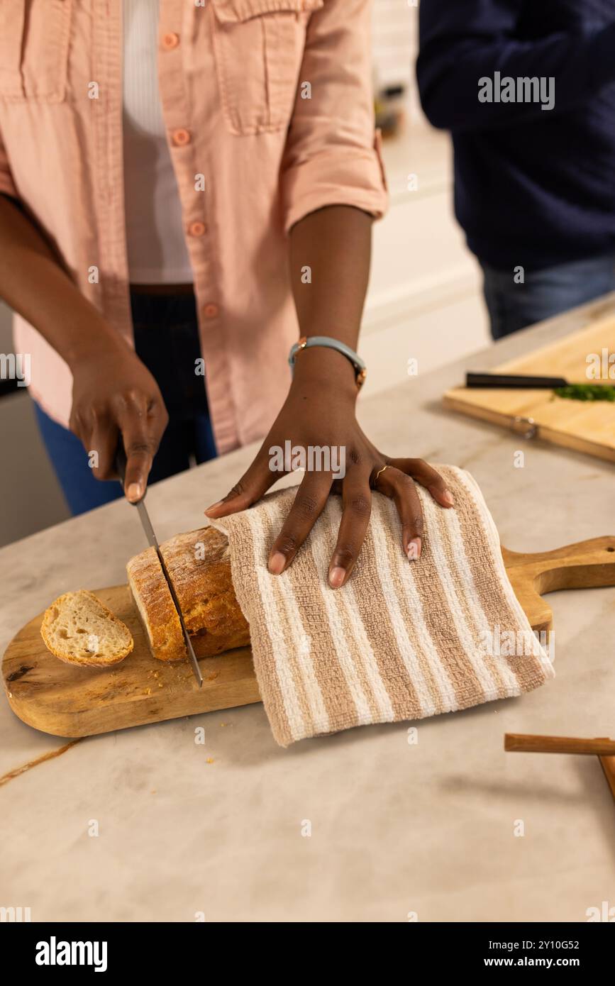 Couper le pain sur une planche de bois, personne préparant le repas dans la cuisine à la maison. Cuisine, fait maison, préparation des repas, tranchage, culinaire, national Banque D'Images