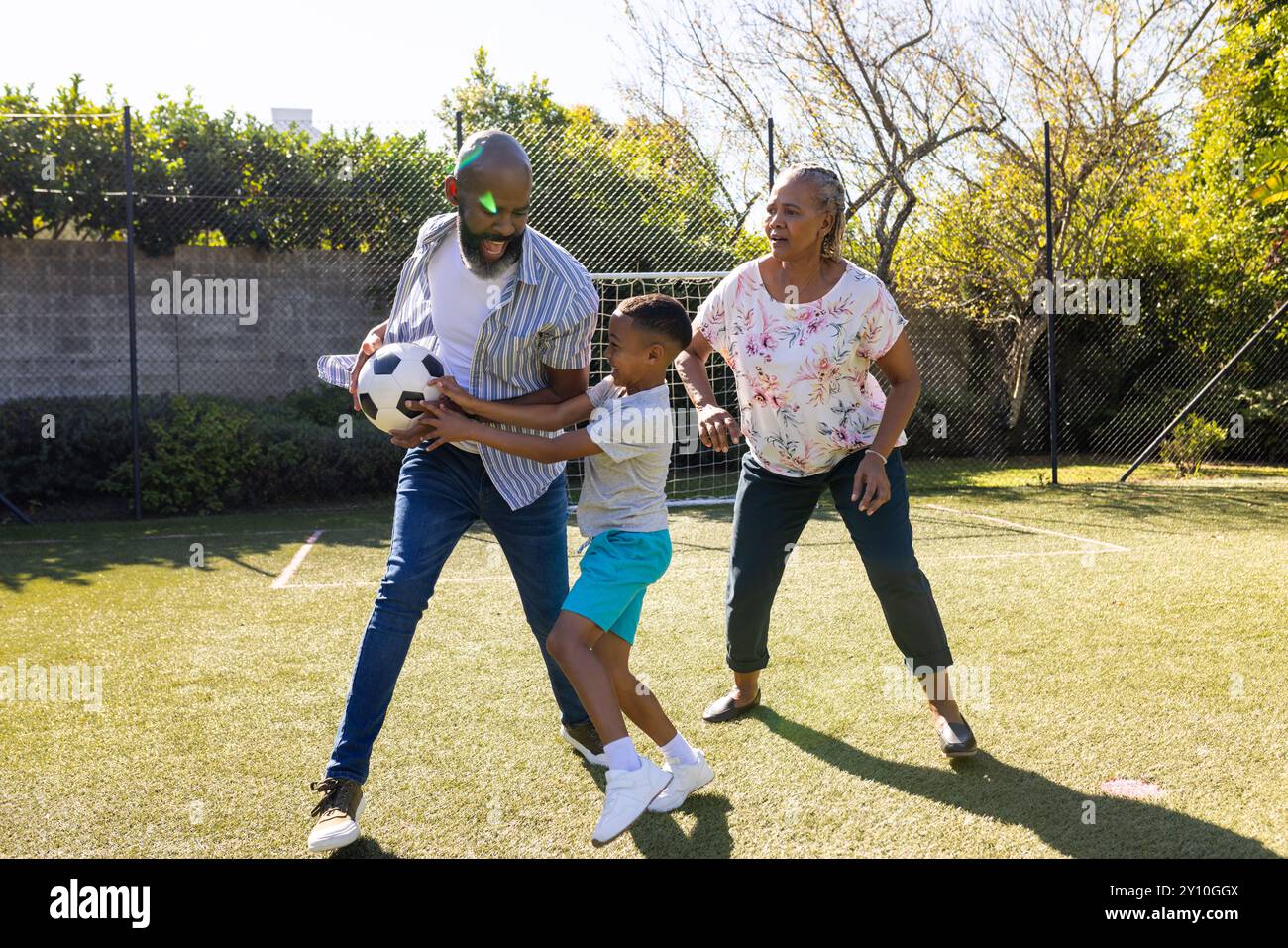 Jouer au football dans la cour arrière, grands-parents et petit-fils profitant du temps en plein air ensemble Banque D'Images