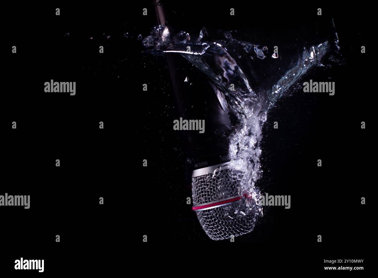 Microphone éclaboussant dans l'eau sur fond noir Banque D'Images