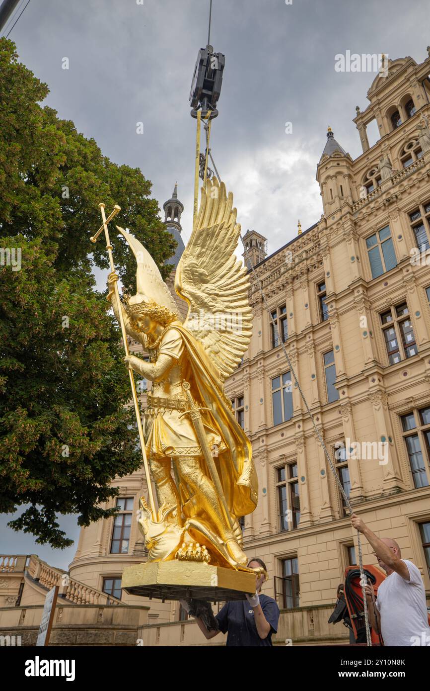 Schwerin, Allemagne. 04th Sep, 2024. L'Archange Michel retourna sur le magnifique dôme du château de Schwerin. Après plusieurs mois de travaux de restauration, la figurine d'environ 900 kilogrammes de l'Archange Michel est retournée dans le magnifique dôme du château de Schwerin. L'Archange Michel, tuant le dragon - le nom officiel de la figure en zinc moulé de 1857 - a été restauré pour la dernière fois il y a 30 ans, et l'ensemble de la résidence Schwerin - qui comprend le palais - est un site du patrimoine mondial de l'UNESCO depuis la fin du mois de juillet. Crédit : Ulrich Perrey/dpa/Alamy Live News Banque D'Images