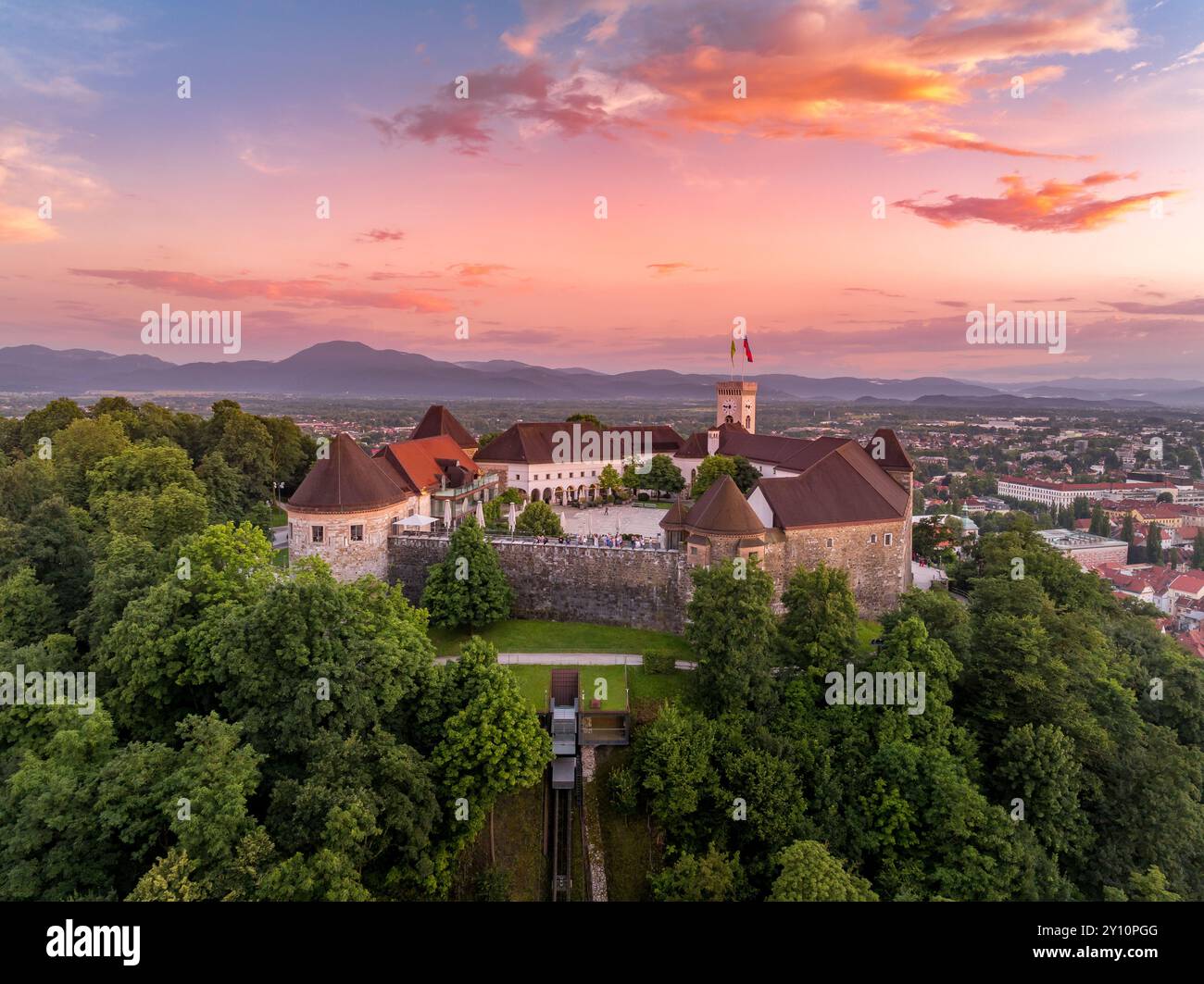 Vue aérienne du coucher du soleil du château de Ljubljana en Slovénie, tours, bastions, funiculaire emmenant les visiteurs jusqu'à la colline au ciel coloré Banque D'Images