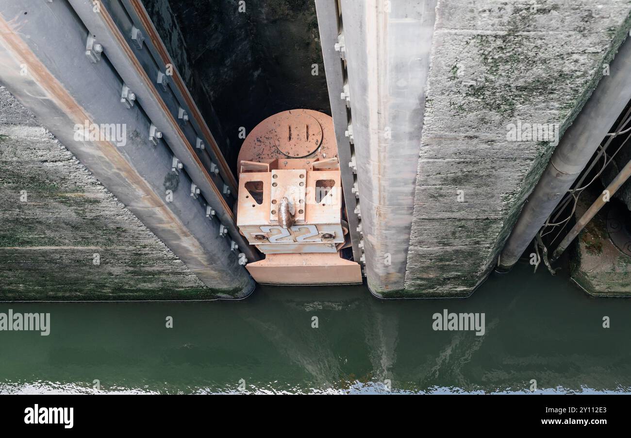 Mécanisme massif de porte de verrouillage avec des murs en béton et de l'eau verte Banque D'Images