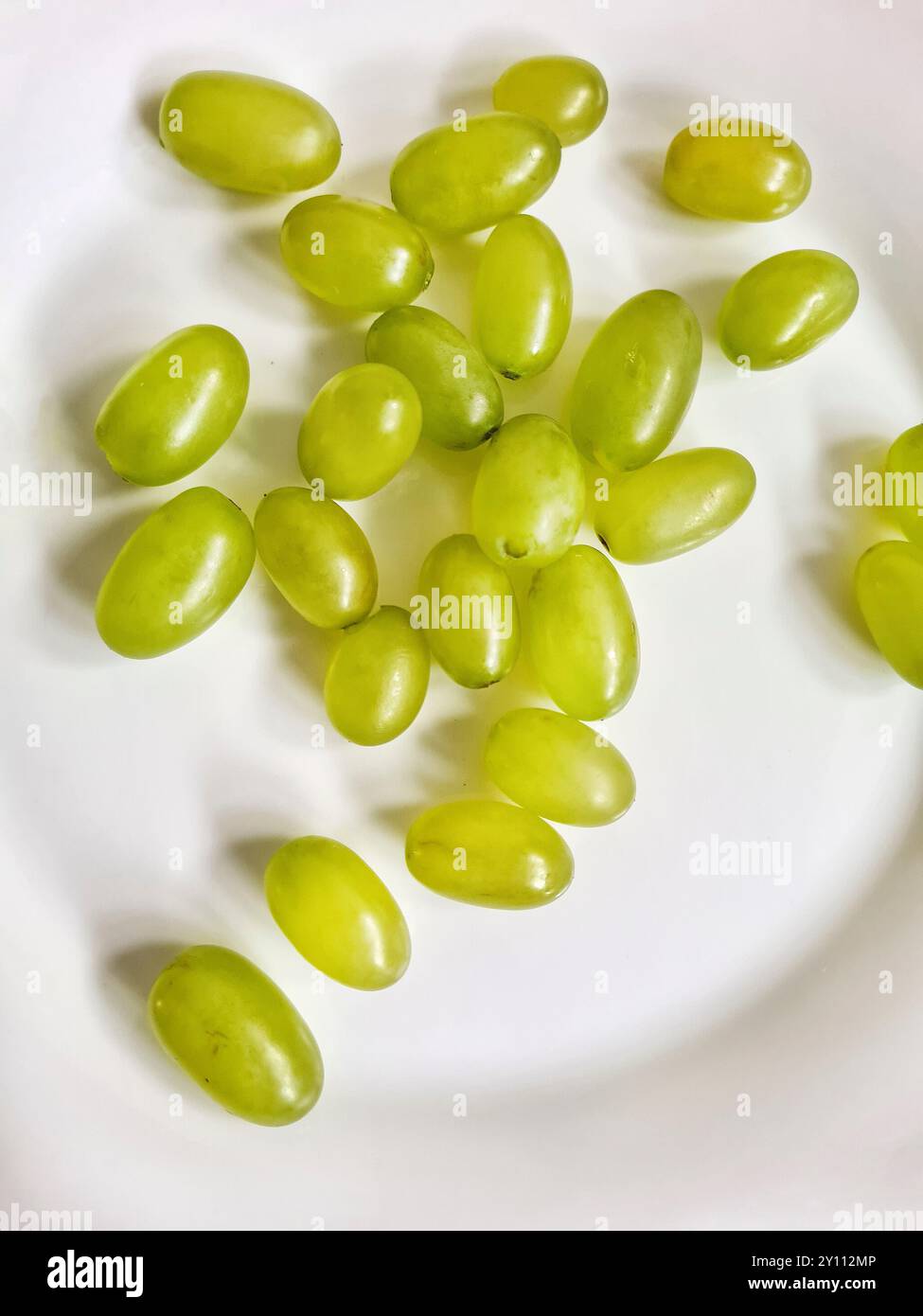 Raisins frais en vrac vert clair sur une assiette blanche, fruits comme régime riche en vitamines en été ou nourriture pour les régimes Banque D'Images