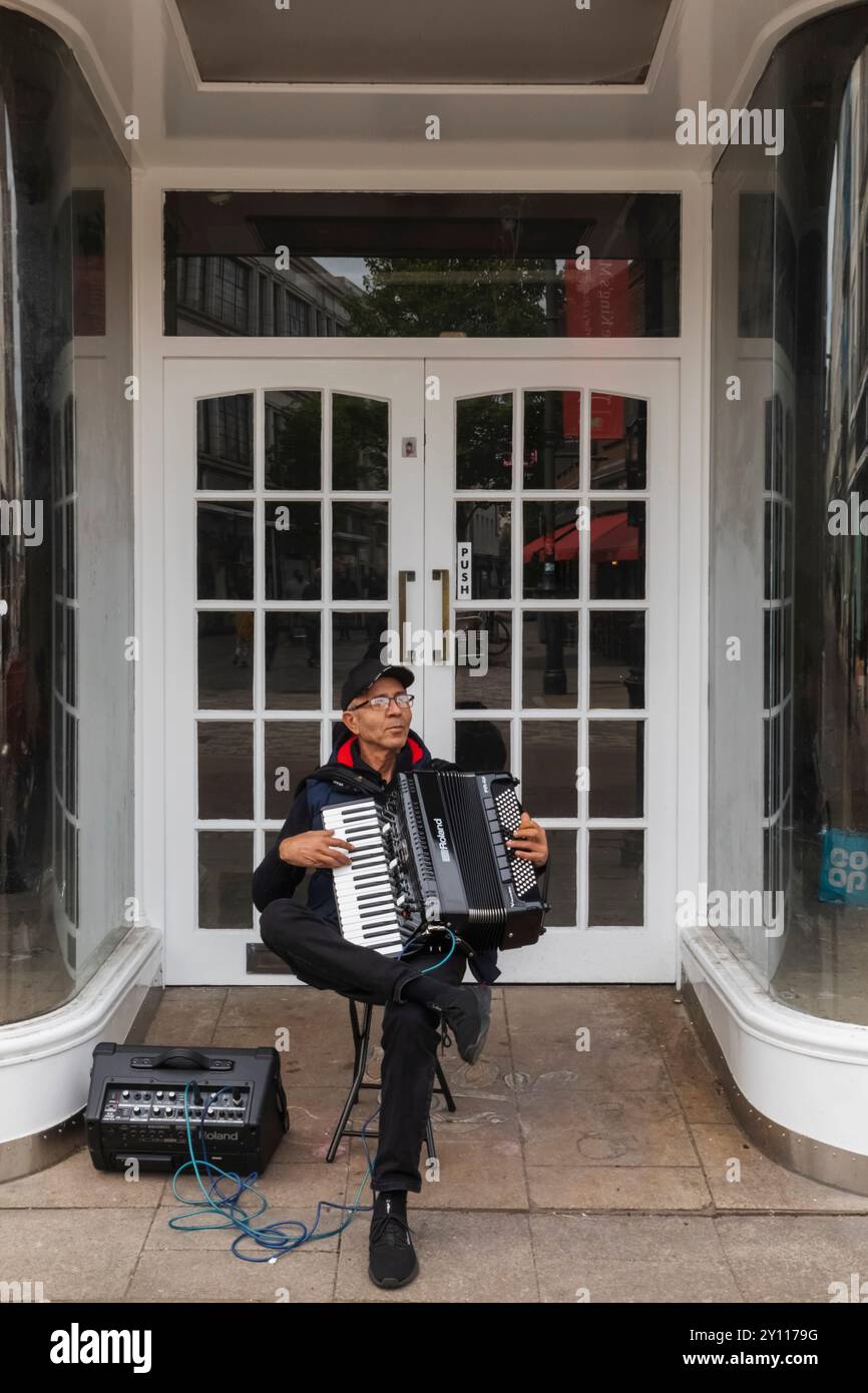 Angleterre, Kent, Canterbury, The High Street, busker jouant Accordian dans la porte du magasin Banque D'Images