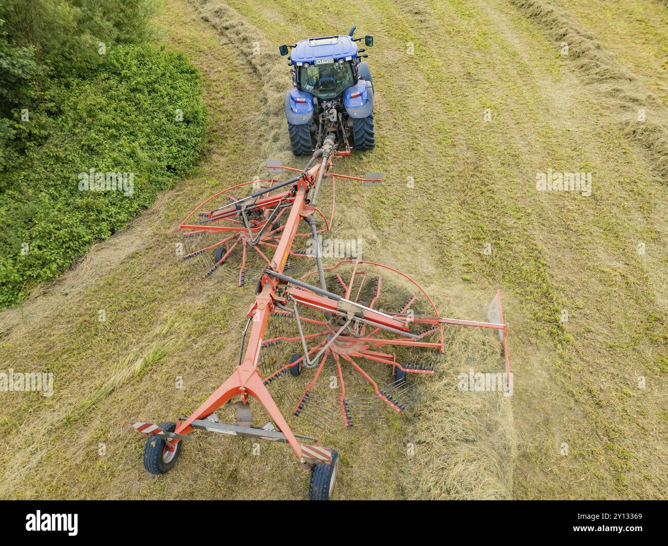 Vue aérienne d'un tracteur avec machine à foin dans un champ, entouré d'herbe coupée et de balles de foin, Dachtel. Forêt Noire, Allemagne, Europe Banque D'Images