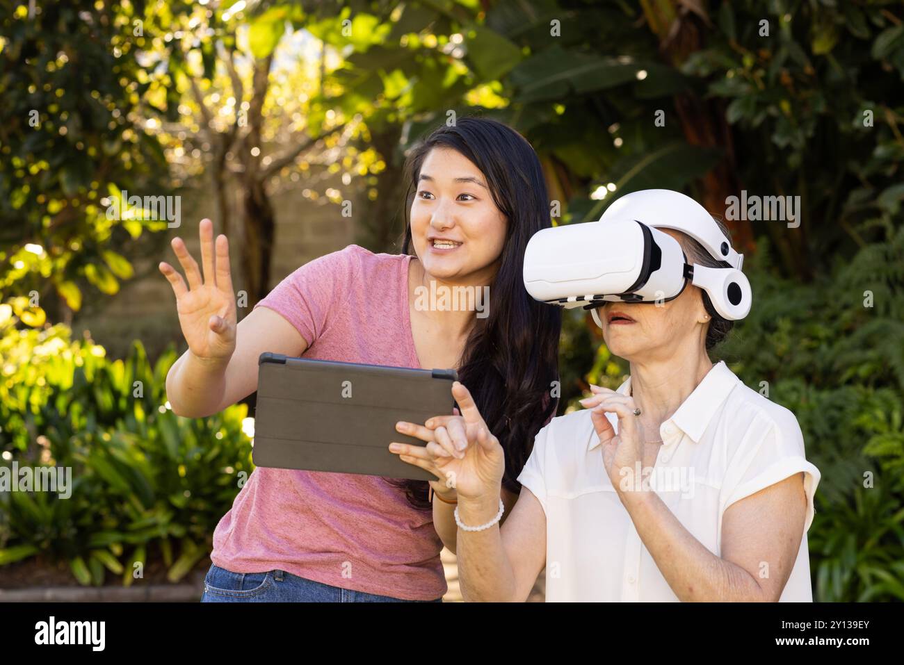 En utilisant un casque VR, grand-mère asiatique explorant la réalité virtuelle avec de l'aide à l'extérieur Banque D'Images