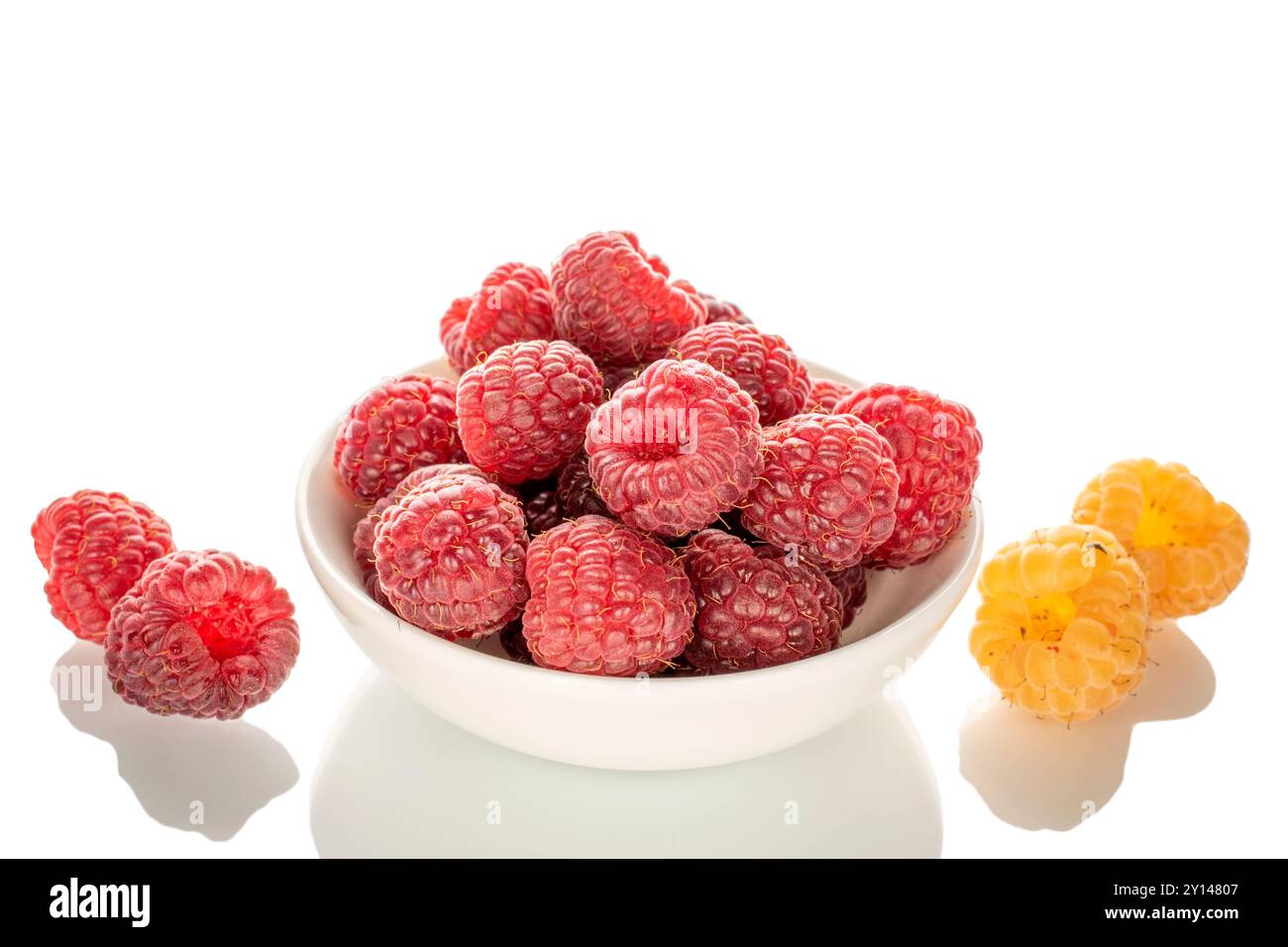 Baies de framboises fraîches sur une soucoupe en céramique, macro, isolées sur fond blanc. Banque D'Images