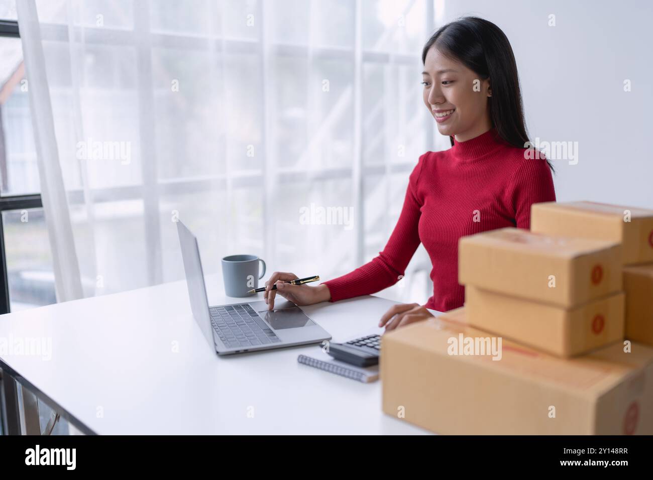 femme, vendeuse en ligne, gère efficacement les commandes des clients et la livraison via la plateforme e-commerce. Banque D'Images