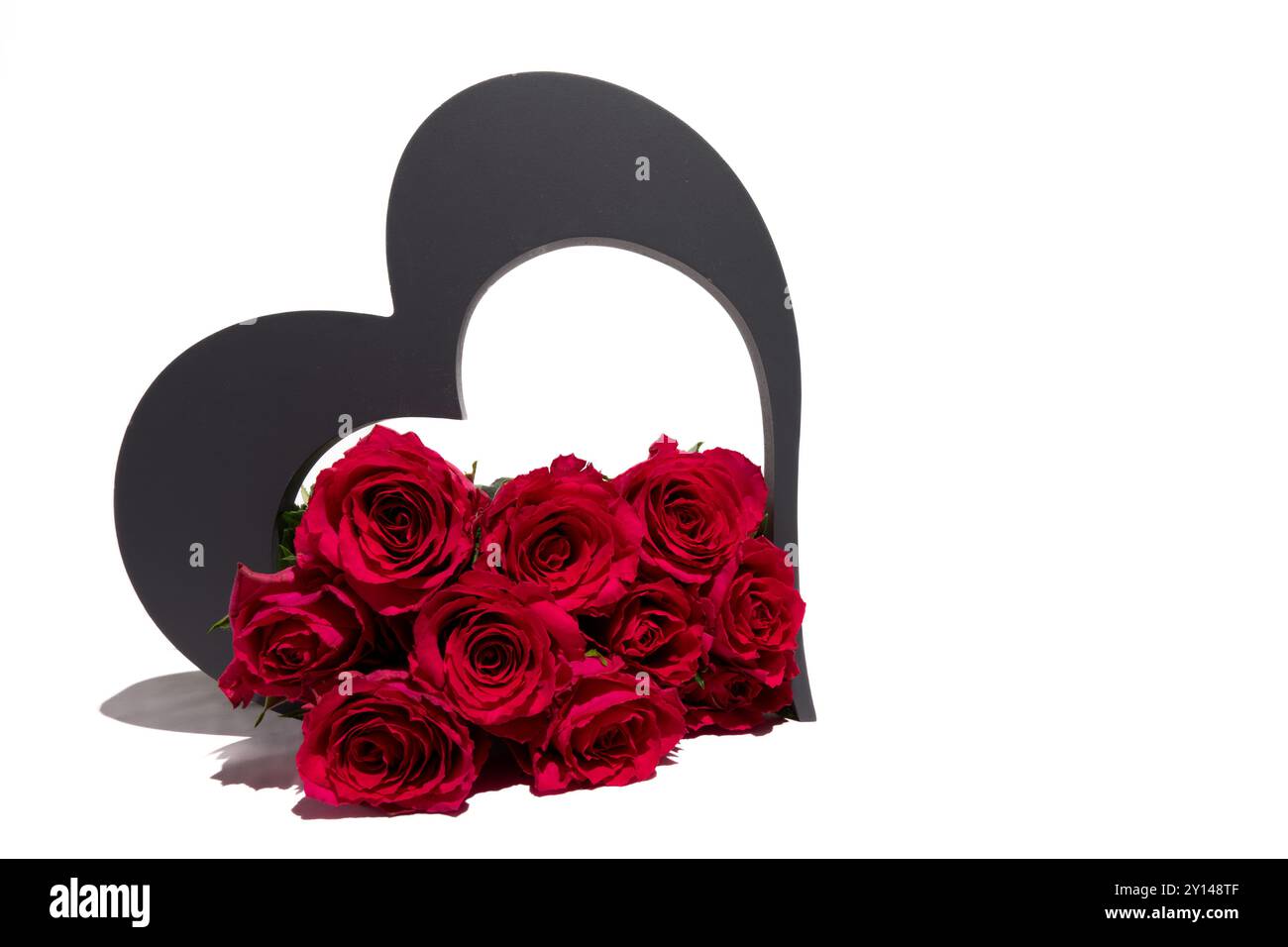 Un groupe de roses rouges vibrantes disposées soigneusement devant une forme de coeur. Les roses sont en pleine floraison, mettant en valeur leur couleur vive. Banque D'Images