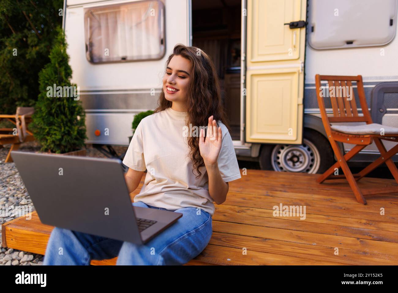 Une heureuse femme agite en regardant la caméra lors d'un appel vidéo depuis son fourgon de camping Banque D'Images