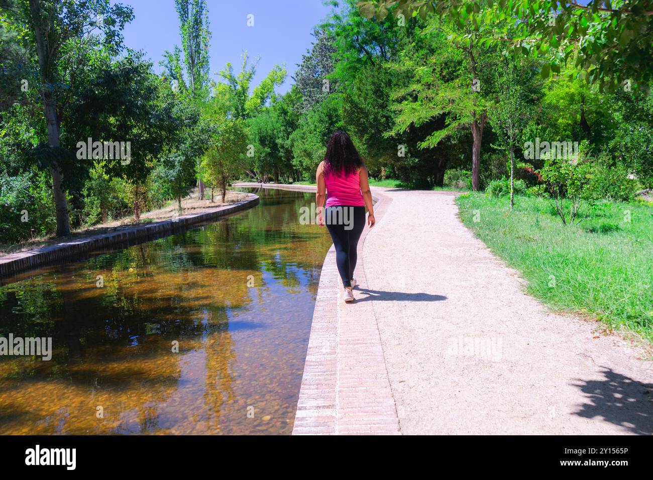 Jeune femme marchant sur le chemin de la rivière dans le parc. Banque D'Images