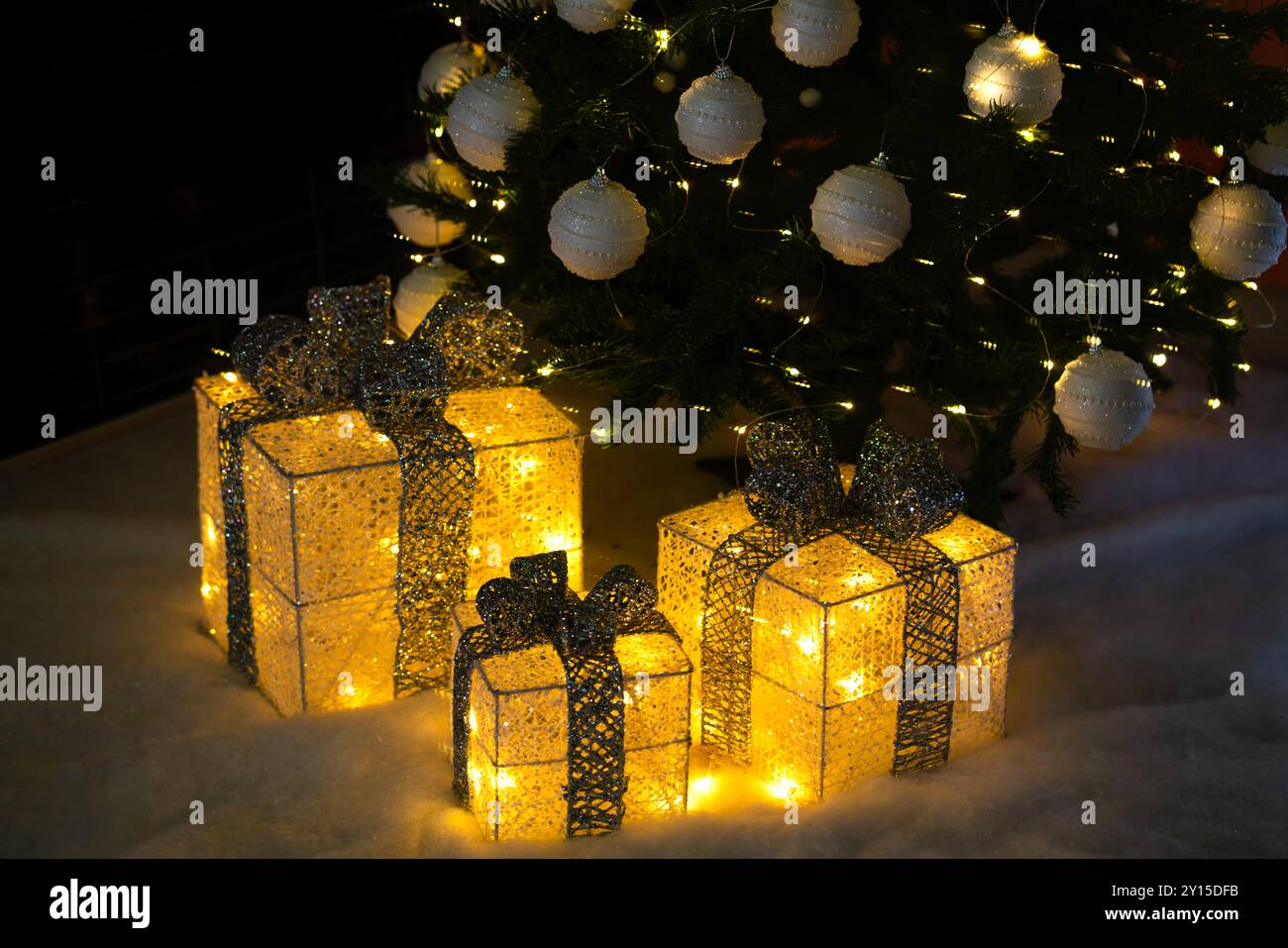 Décor de boîtes brillantes dorées avec des arcs sous le sapin de Noël. Bannière de la Saint-Sylvestre. La veille du nouvel an, l'arbre est décoré de boules et de lumière Banque D'Images