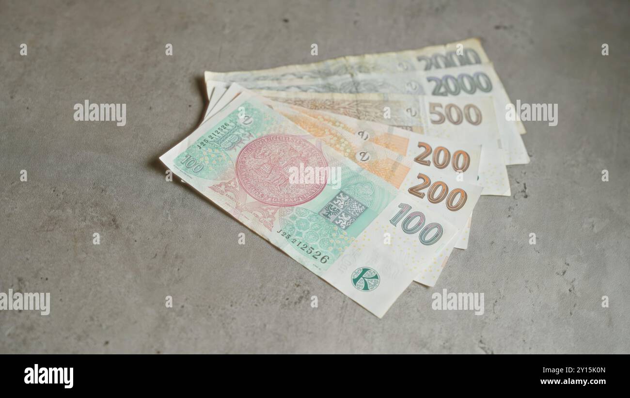 Les billets de banque en couronnes tchèques se sont étalés sur une surface en béton, mettant en vedette différentes monnaies de la république tchèque. Banque D'Images