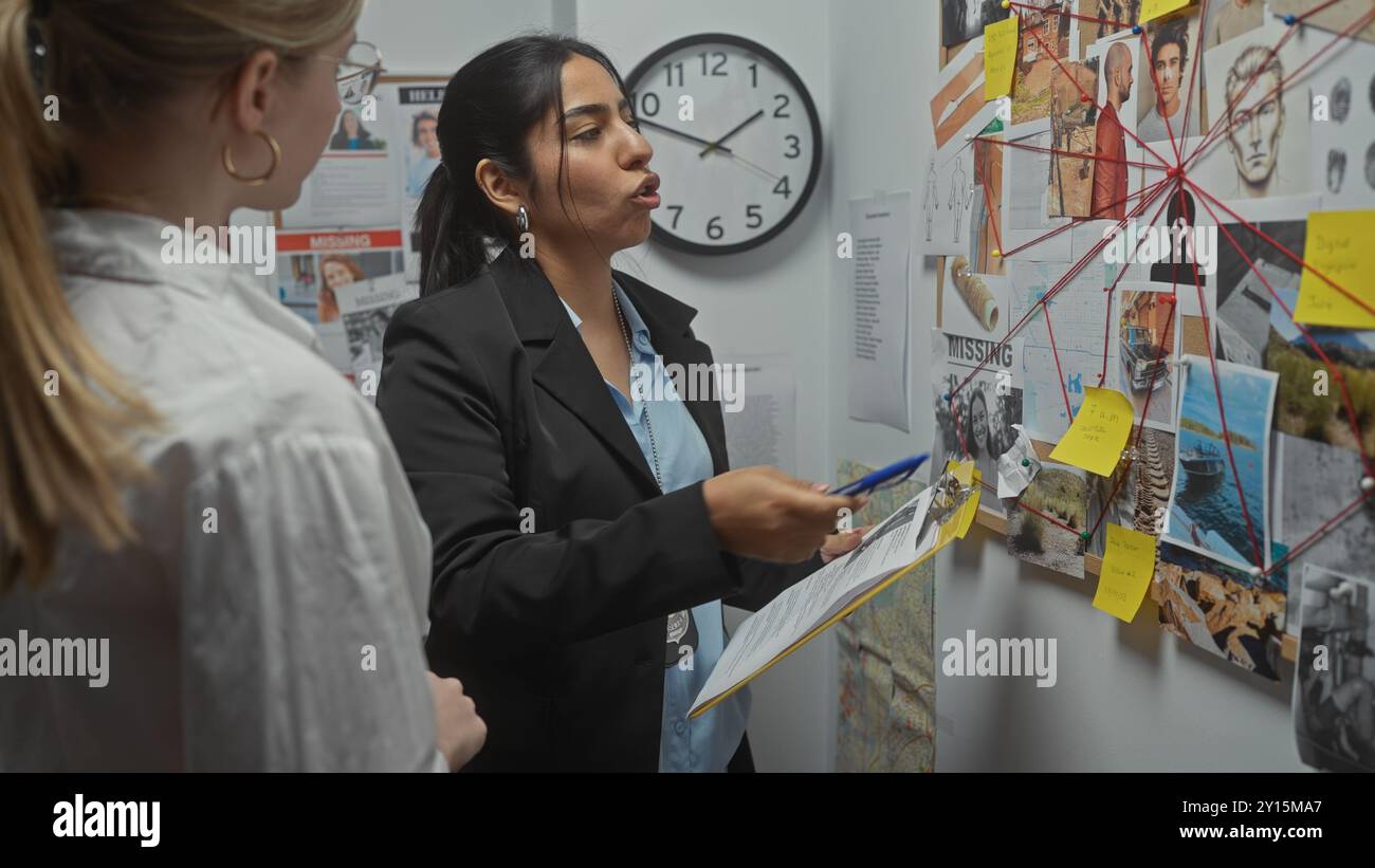 Deux femmes enquêtrices analysent les preuves sur un tableau dans un bureau de poste de police. Banque D'Images