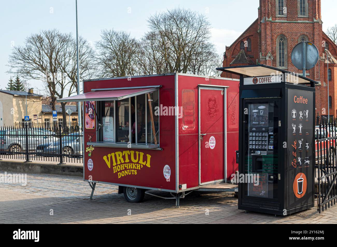 Liepaja, Lettonie - Mart 19, 2023 : un camion alimentaire dynamique vendant des beignets est garé à côté d'un kiosque à café en plein jour. Banque D'Images