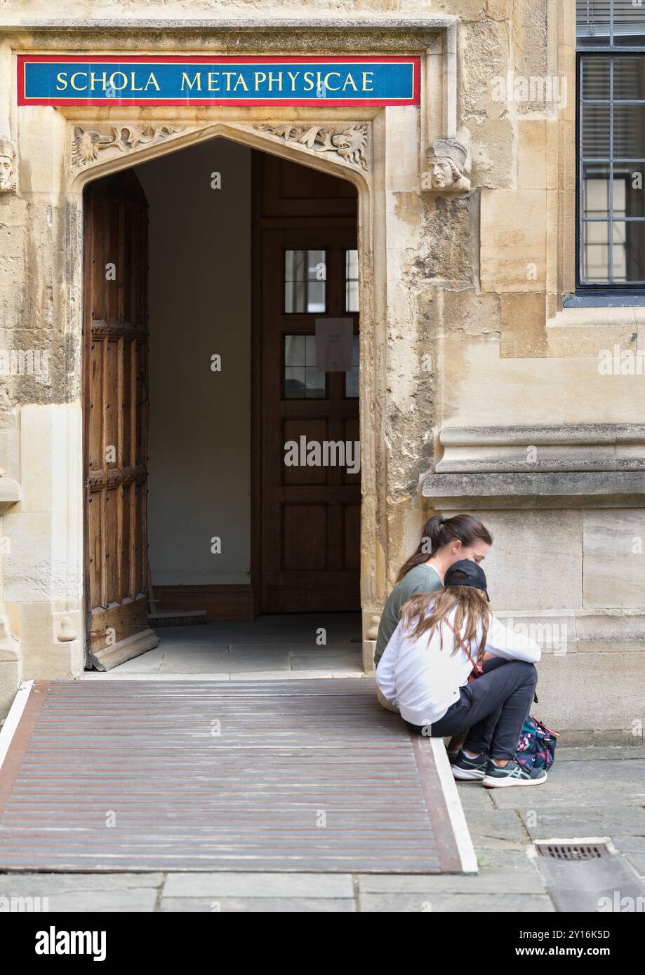 Deux personnes sont assises près de la porte ouverte (à l'école de métaphysique) dans l'ancienne bibliothèque, qui fait partie de la bibliothèque Bodleian, Université d'Oxford, Angleterre. Banque D'Images