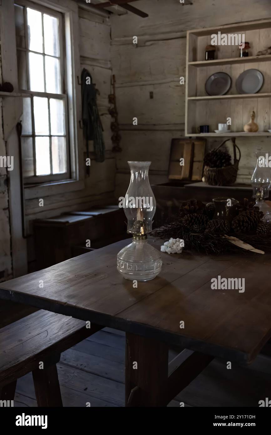 Gros plan de lampe à huile antique sur la table de ferme dans la cabane en rondins des années 1800 avec cuisine historiquement précise Banque D'Images