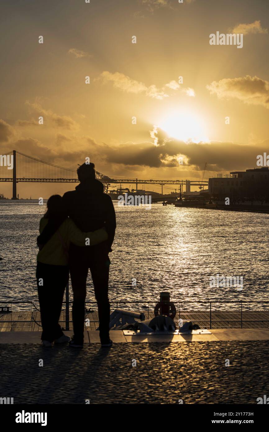 Coucher du soleil sur le port de Lisbonne - depuis le quai de la Praca do Comercio, en regardant le Tage vers les ponts et Belem. Banque D'Images