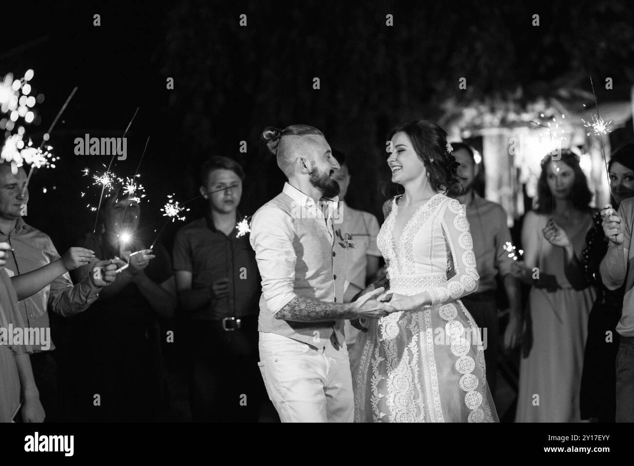 des sparklers au mariage des jeunes mariés entre les mains d'invités joyeux Banque D'Images