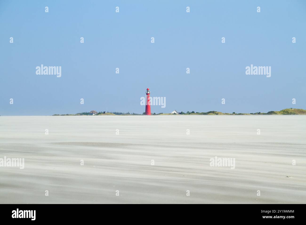 Vue sur une vaste plage de sable à la dérive causée par le vent fort sur le phare rouge de l'île hollandaise Schiermonnikoog Banque D'Images
