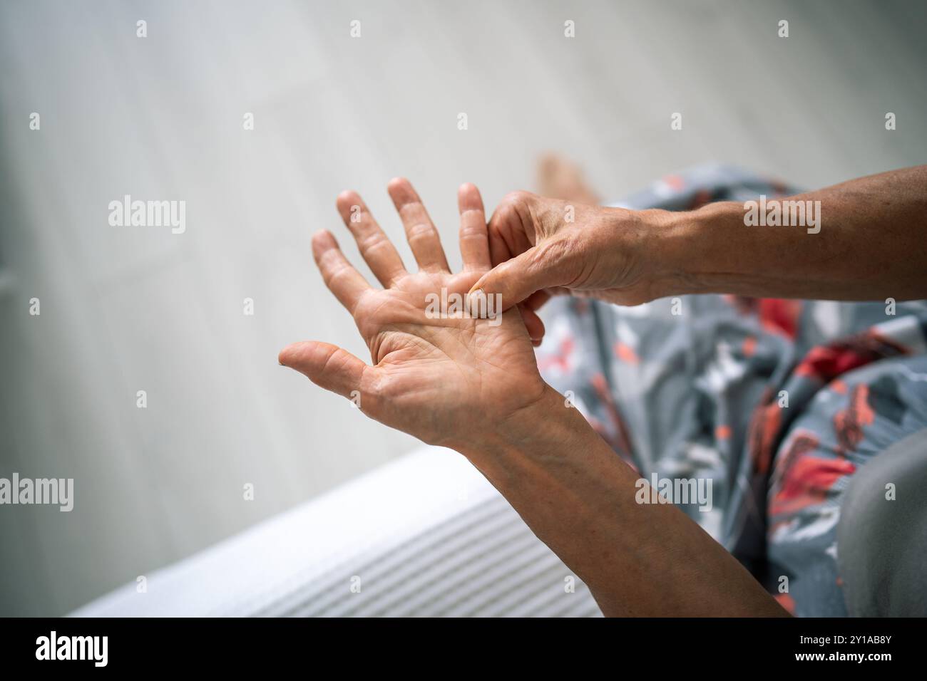 Une vieille femme invisible frotte, se sent la main tendre avec un nœud raide sous l'annulaire. La contracture de Dupuytren Banque D'Images