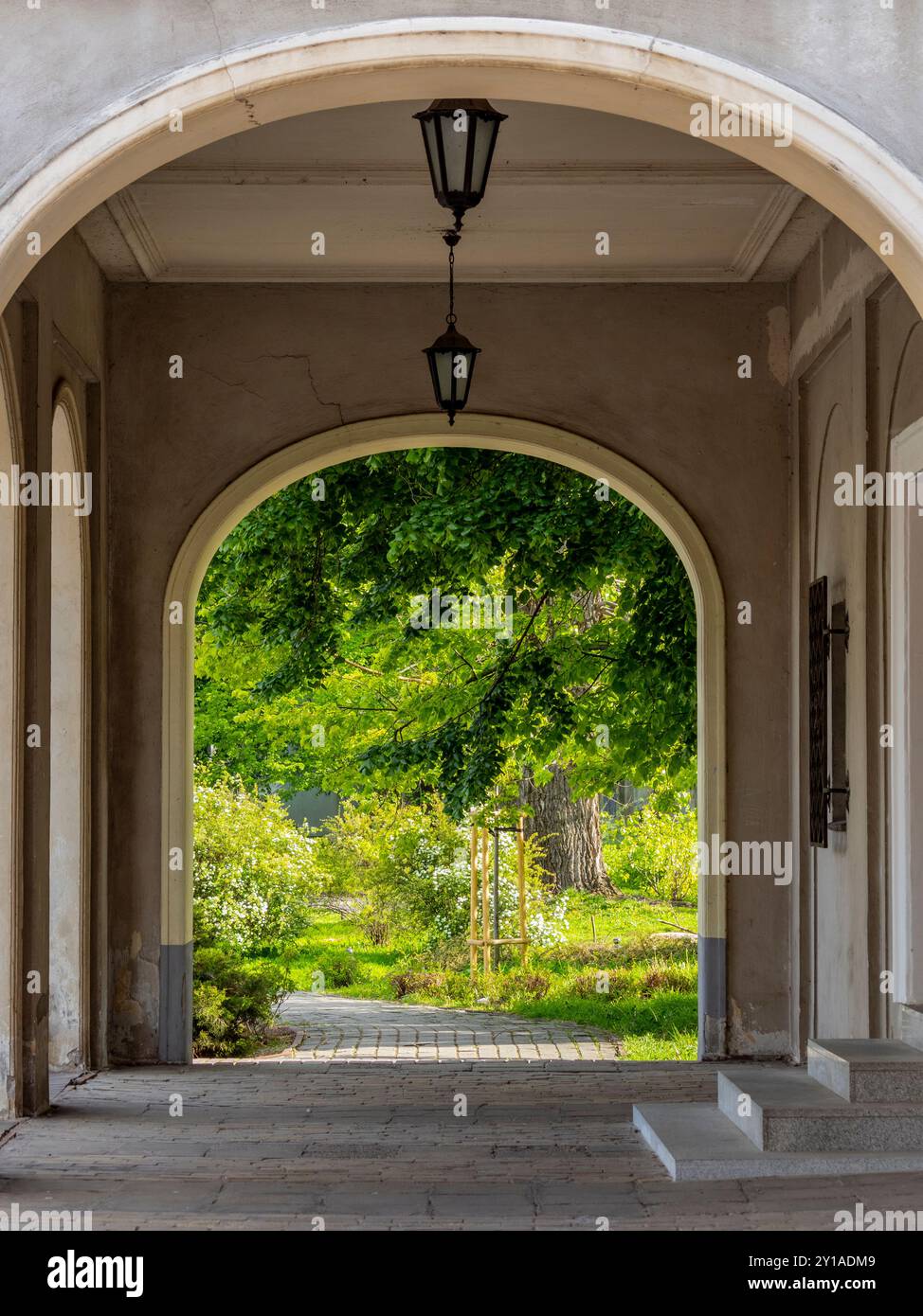 Les arcades de l'ancien bâtiment et une vue sur le beau, conte de fées, jardin verdoyant aux rayons du soleil. Banque D'Images