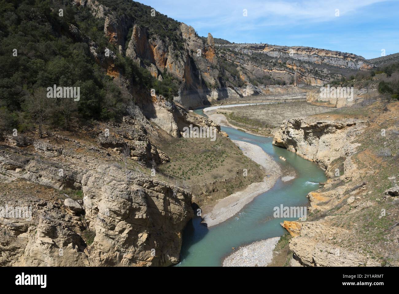 Une rivière claire coule à travers une gorge rocheuse entre des montagnes envahies par la végétation sous un ciel bleu, Parc naturel Noguera Ribagorcana Mont-Rebei, montagne Montsec Banque D'Images