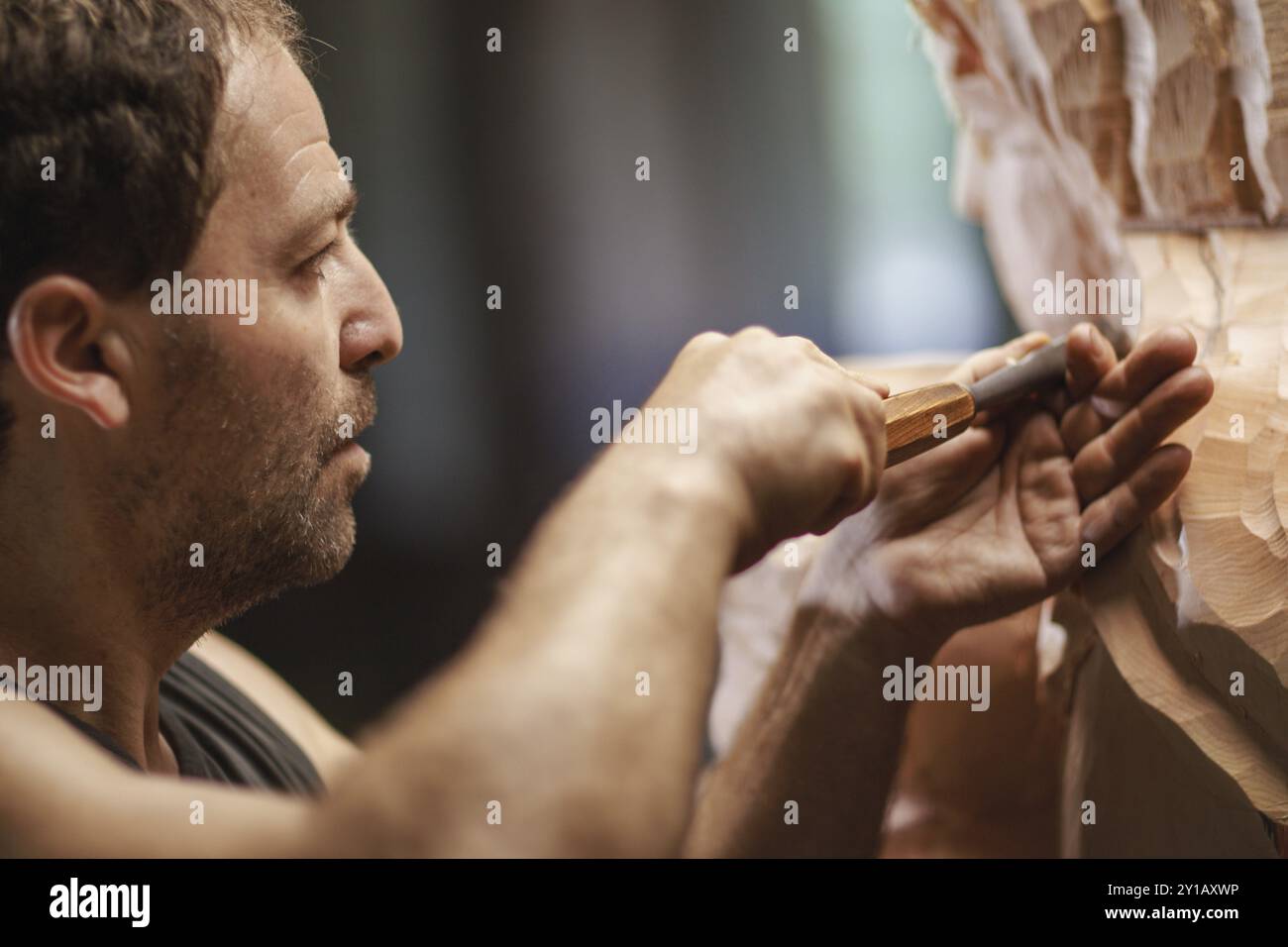 Un artisan utilise soigneusement un ciseau pour façonner une grande sculpture en bois avec précision Banque D'Images